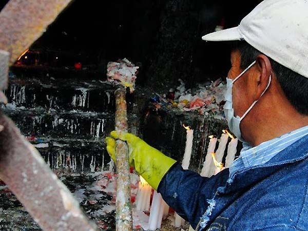 Operario limpiando cera de las velas de un altar en Las Lajas